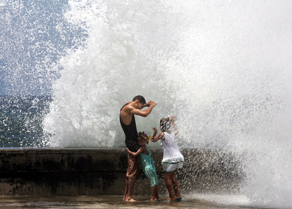 A Cuban father and his two daughters enjoy the waves battering against Havana's seafront El Malecon, September 5, 2004. Hurricane Frances caused high waves and strong winds in the Cuban capital before being downgraded as a tropical storm over Florida. REUTERS/Claudia Daut NO RIGHTS CLEARANCES OR PERMISSIONS ARE REQUIRED FOR THIS IMAGE CD - RP5DRHXRZLAC