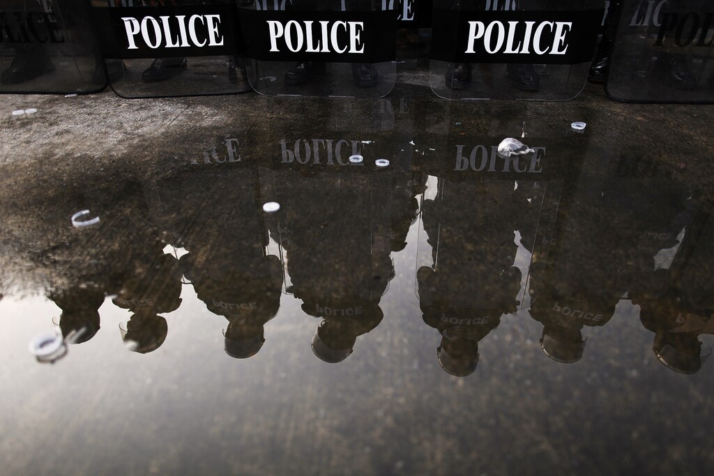 Thai riot policemen are reflected in water behind their shields as they take a part in an exercise in an army base in Bangkok's suburbs February 20, 2010. Thai security forces, army and police organized a joint exercise to prepare for possible anti-government protests in the country. REUTERS/Damir Sagolj (THAILAND - Tags: POLITICS CIVIL UNREST MILITARY) - GM1E62K1HUZ01