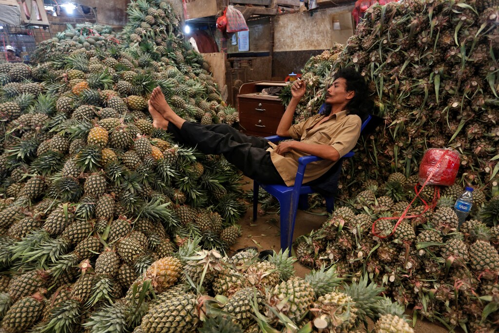 A worker rests beside piles of pineapple at the Kramat Jati wholesale market in Jakarta, Indonesia May 1, 2018. Picture taken May 1, 2018. REUTERS/Willy Kurniawan