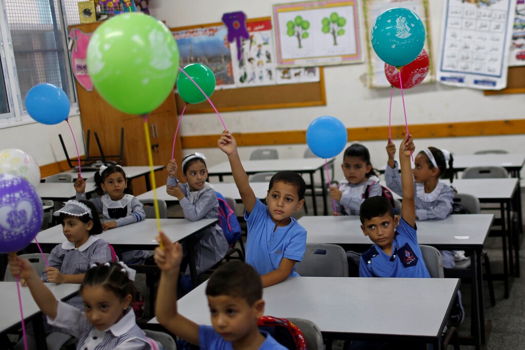 Palestinian students holding balloons sit in a classroom at a United Nations-run school as a new school year begins amid concerns about the spread of the coronavirus disease (COVID-19), in Gaza City August 8, 2020. REUTERS/Mohammed Salem - RC2K9I95BBL9