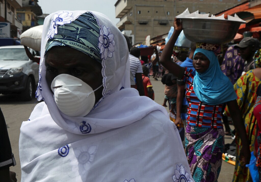 A woman wears a protective mask as she walks on a street in Abidjan, Ivory Coast.