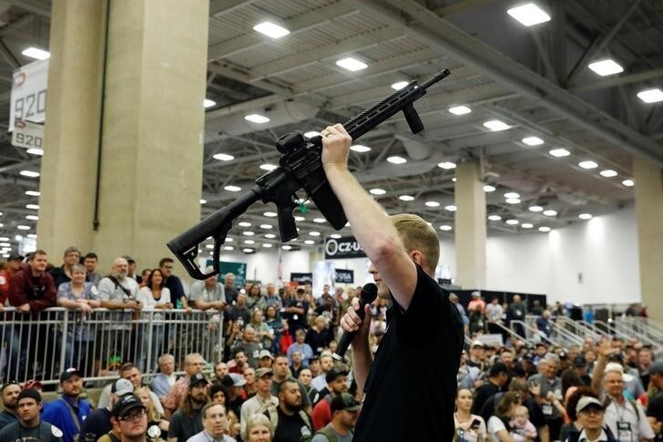 A Daniel Defense employee holds a rifle aloft before a raffle during the annual National Rifle Association (NRA) convention in Dallas, Texas, U.S., May 6, 2018. REUTERS/Lucas Jackson