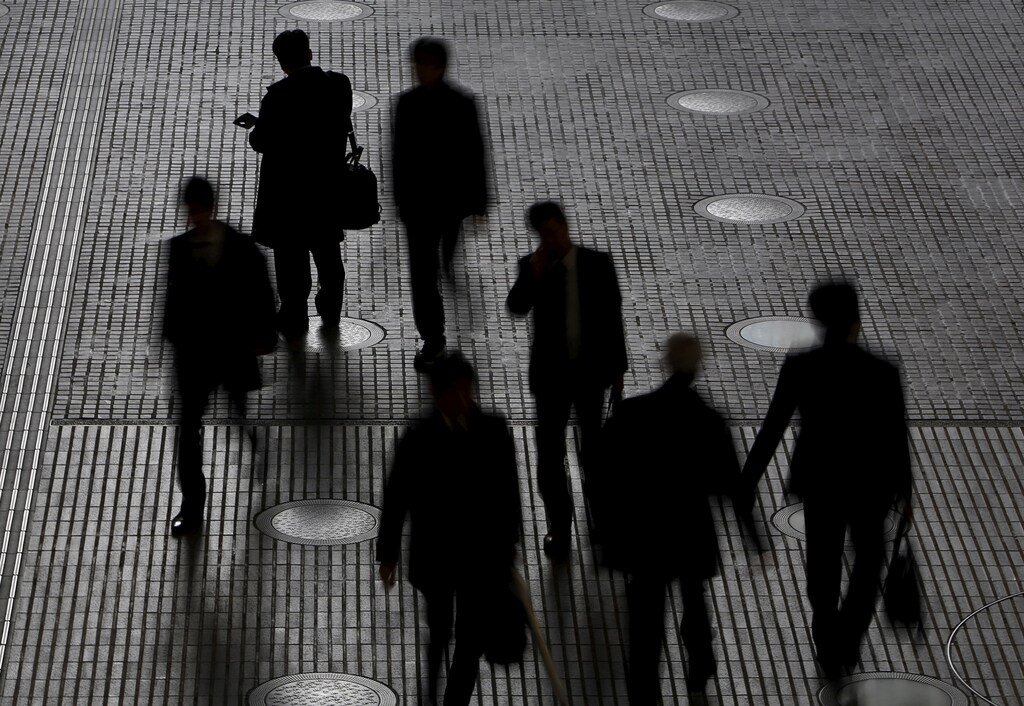 People walk at an office building at a business district in Tokyo, Japan, February 29, 2016.