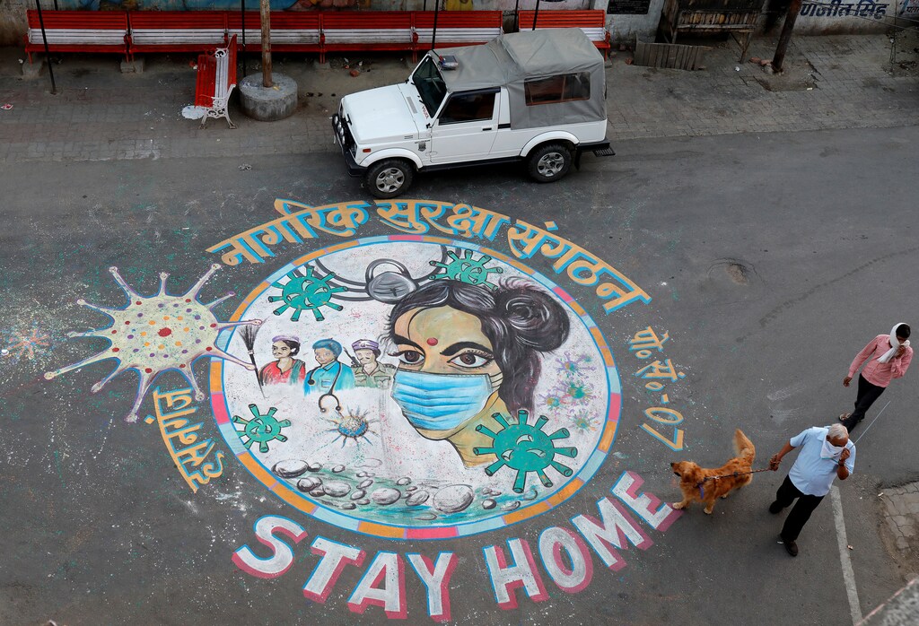 A man walks his dog past a graffiti on a road to create awareness about staying at home during an extended nationwide lockdown to slow the spreading of coronavirus disease (COVID-19) in Lucknow, India, April 22, 2020. REUTERS/Pawan Kumar - RC2Q9G9J4A7D