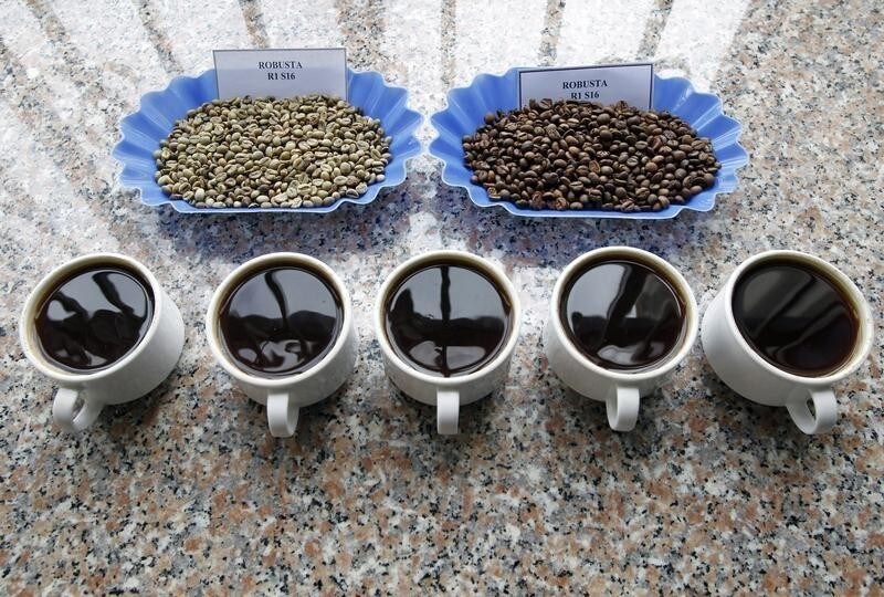 Coffee beans (top L) and roasted coffee beans (top R) are placed near cups of boiled coffee for tasters at a quality control centre in Vietnam's central highland city of Bao Loc December 14, 2011. Vietnam's coffee exports more than doubled in November from the previous month, taking shipments so far this year to 1.1 million tonnes, up 4.4 percent from the year-ago period, keeping prices under pressure. REUTERS/Kham (VIETNAM - Tags: BUSINESS FOOD) - GM1E7CE1O1101