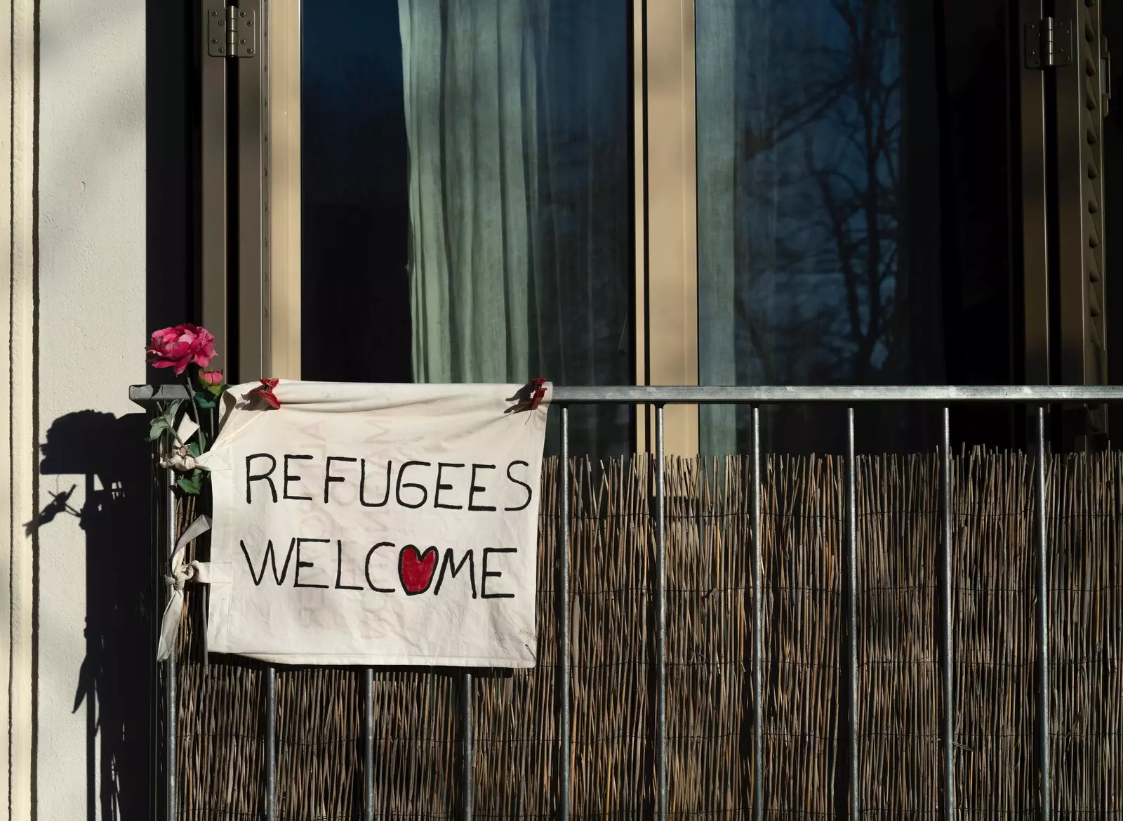 A sign hangs on a balcony and reads "refugees welcome."