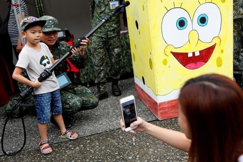 A child poses with a soldier during a public fair which displays military equipments, in Taipei, Taiwan September 29, 2018.