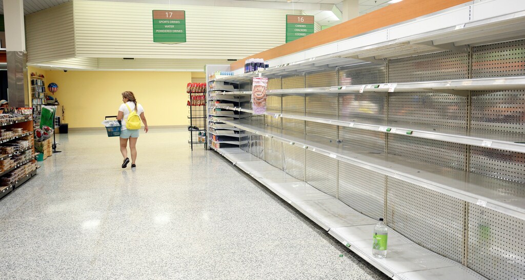 A shopper walks past empty shelves, which would normally be stocked with water, at a supermarket ahead of Hurricane Irma making landfall in Kissimmee, Florida, September 9, 2017. REUTERS/Gregg Newton - RC13E8219000