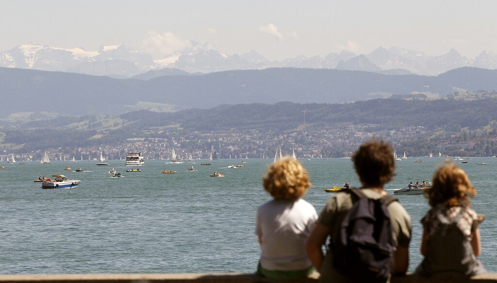 People sit on a wall on the banks of Lake Zurich during sunny summer weather in Zurich July 3, 2011. REUTERS/Arnd Wiegmann