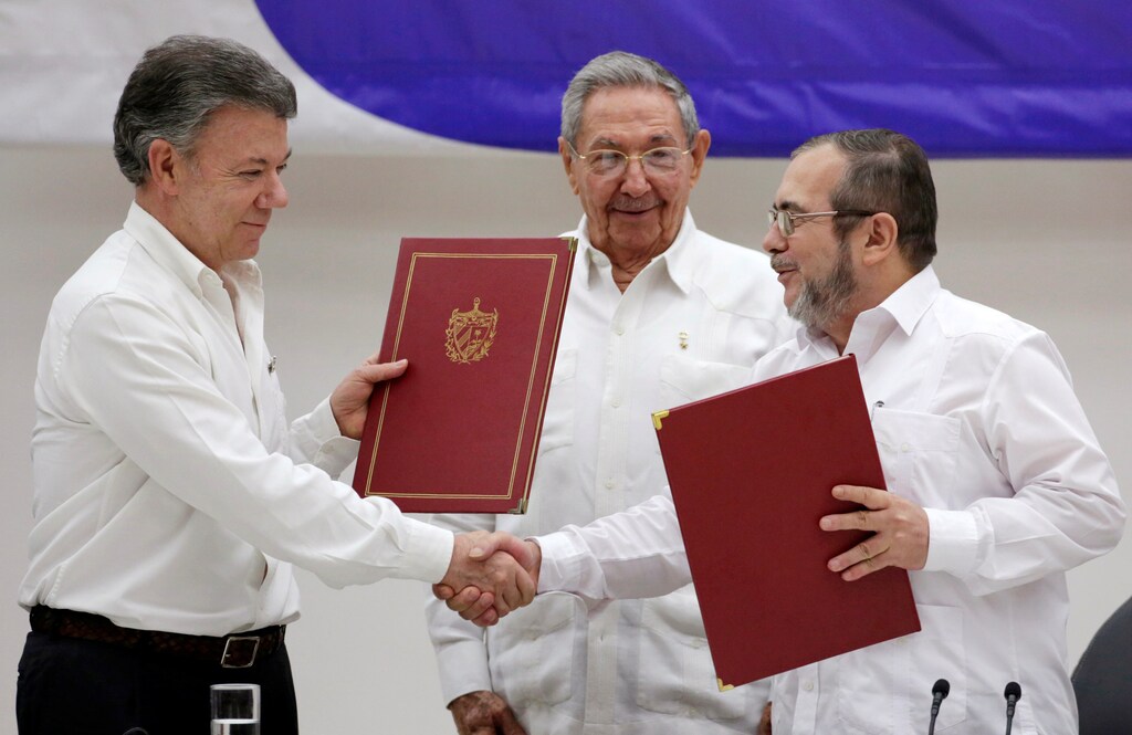 Cuba's President Raul Castro (C), Colombia's President Juan Manuel Santos (L) and FARC rebel leader Rodrigo Londono, better known by his nom de guerre Timochenko, react after the signing of a historic ceasefire deal between the Colombian government and FARC rebels in Havana, Cuba, June 23, 2016. REUTERS/Enrique de la Osa - RTX2HV5L
