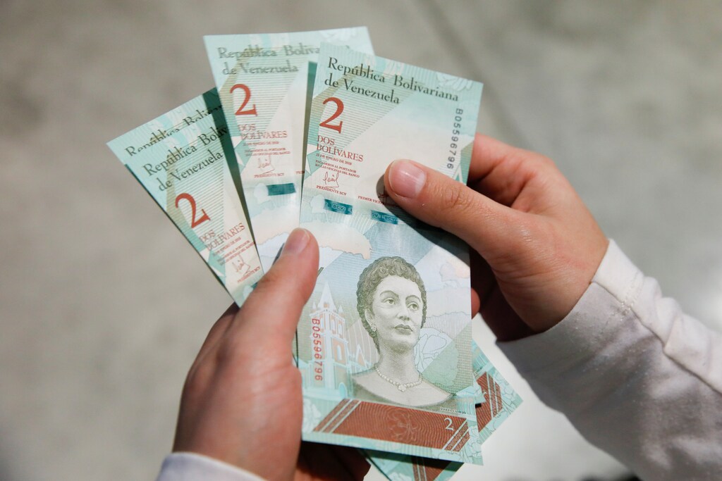 A woman shows the new two Bolivar Soberano (Sovereign Bolivar) bills, after she withdrew them from an automated teller machine (ATM) at the Banesco bank headquarters in Caracas, Venezuela August 20, 2018. REUTERS/Carlos Garcia Rawlins - RC124030E970