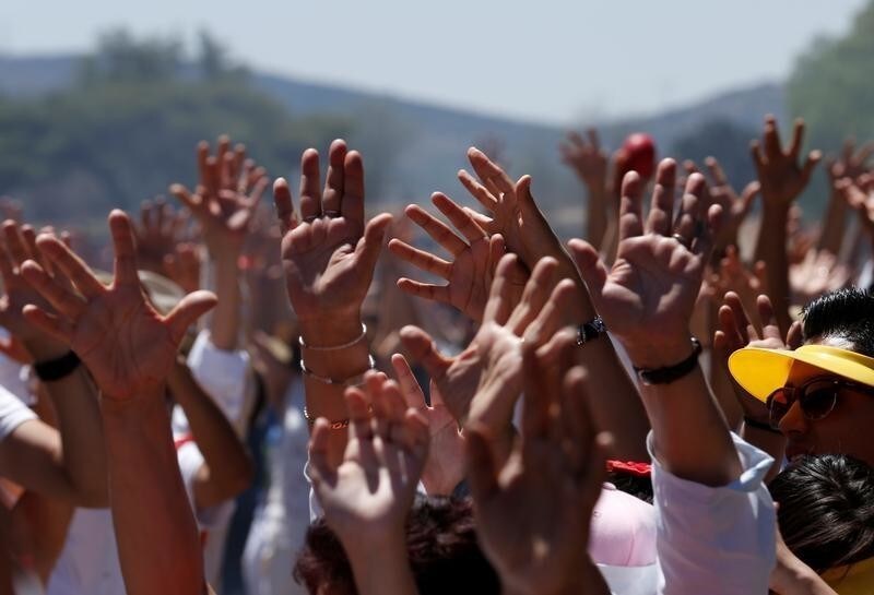 People raise their arms towards the sun to welcome the spring equinox in front of the Pyramid of the Sun in the pre-hispanic city of Teotihuacan, on the outskirts of Mexico City, Mexico, March 20, 2017. REUTERS/Henry Romero - RC199736FC00