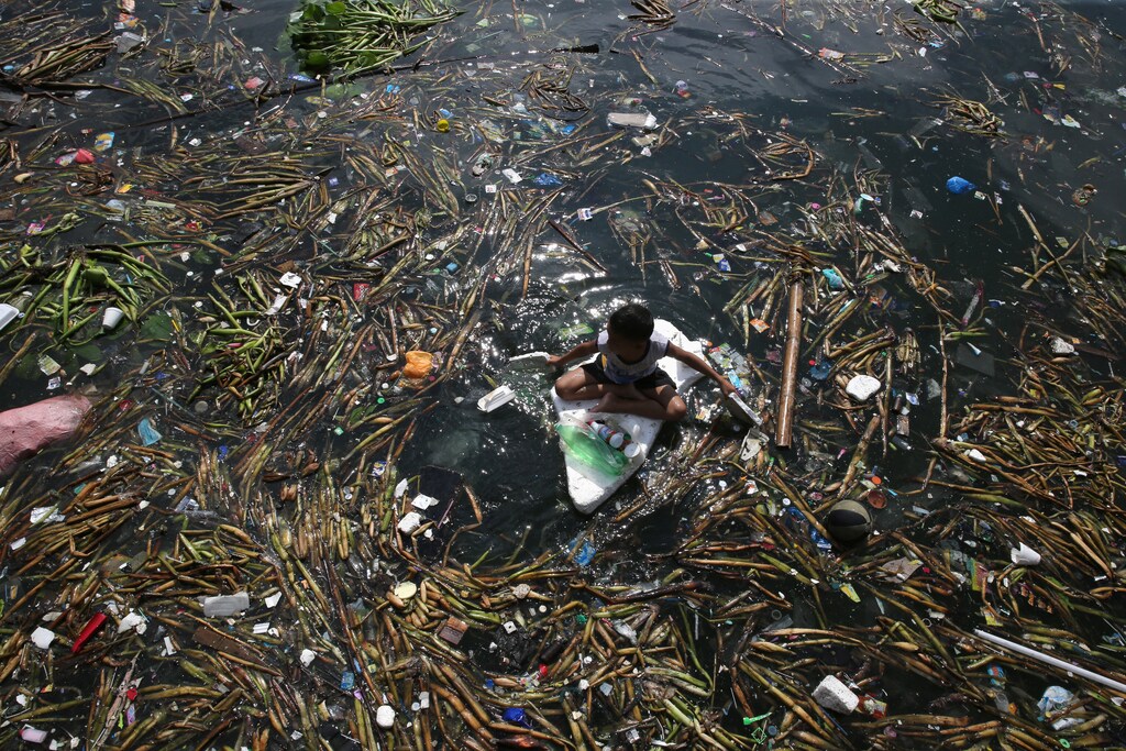 Children float on makeshift raft made of discarded boards and styrofoam as they collect recyclable plastic bottles drifting along the coast of Manila Bay at the slum area in the Baseco Compound in metro Manila, Philippines October 16, 2017. REUTERS/Romeo Ranoco - RC175D36F700