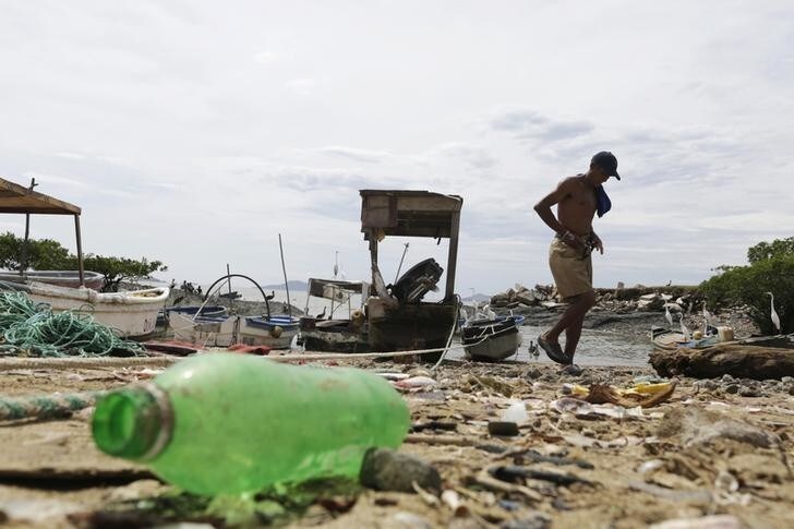 A fisherman walks past a plastic bottle on the beach in Veracruz port on the outskirts of Panama City September 16, 2013. The National Association for the Conservation of Nature (ANCON) reports that the majority of Panama City's beaches and rivers are contaminated with plastic and general waste due to lack of awareness for waste management, causing major problems for fishermen and negative impact on mangroves and their wildlife. According to the Plastic Oceans Foundation, more plastic has been produced over the last ten years than over the whole of the last century. Picture taken September 16, 2013. REUTERS/Carlos Jasso (PANAMA - Tags: ENVIRONMENT SOCIETY)