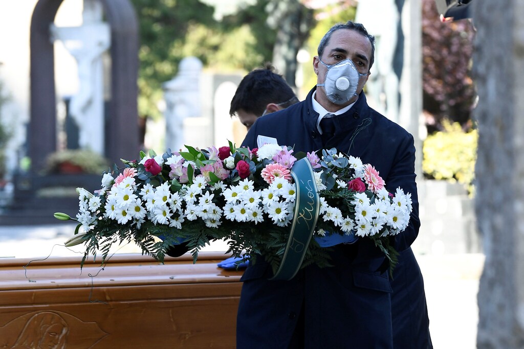 Cemetery workers and funeral agency workers in protective masks transport a coffin of a person who died from coronavirus disease (COVID-19), into a cemetery in Bergamo, Italy March 16, 2020. REUTERS/Flavio Lo Scalzo - RC22LF9DLNKA