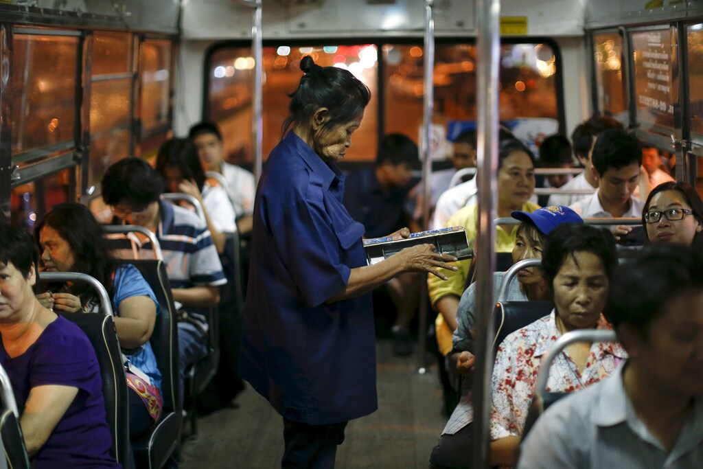 Pranom Chartyothin, a 72-year-old bus conductor, sells and collects bus tickets in downtown Bangkok, Thailand, February 3, 2016. Such scenes will only become more common in Thailand as its population rapidly ages, unlike its neighbours with more youthful populations. The World Bank estimates the working-age population will shrink by 11 percent by 2040, the fastest contraction among Southeast Asia's developing countries. Thailand's stage of economic development, the rising cost of living and education, and a population waiting longer to get married are among the reasons it is ageing more quickly than its neighbours. An effective contraception programme in the 1970s also played a part, said Sutayut Osornprasop, a human development specialist at the World Bank in Thailand. Picture taken February 3, 2016. REUTERS/Jorge Silva TPX IMAGES OF THE DAY - GF10000302961