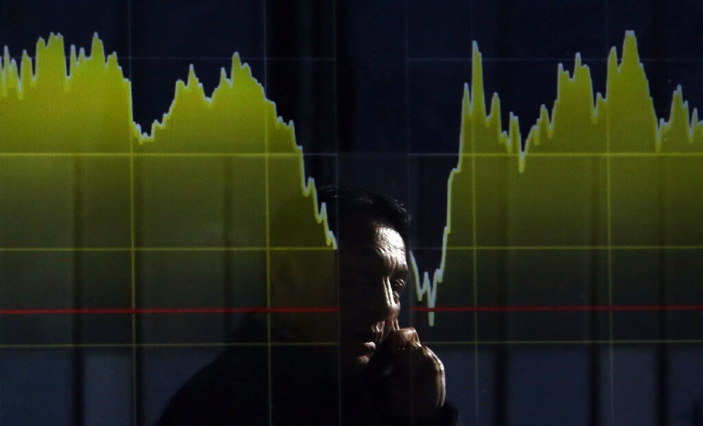 A pedestrian holding his mobile phone is reflected on an electronic board showing the graph of the recent fluctuations of Japan's Nikkei average outside a brokerage in Tokyo February 5, 2014. The Nikkei average rose 1.2 percent in a volatile session on Wednesday, rebounding from a four-month low as investors scooped up recently battered stocks such as Panasonic and Toyota Motor following strong earnings reports. REUTERS/Yuya Shino (JAPAN - Tags: BUSINESS TPX IMAGES OF THE DAY) - GM1EA2516EX01