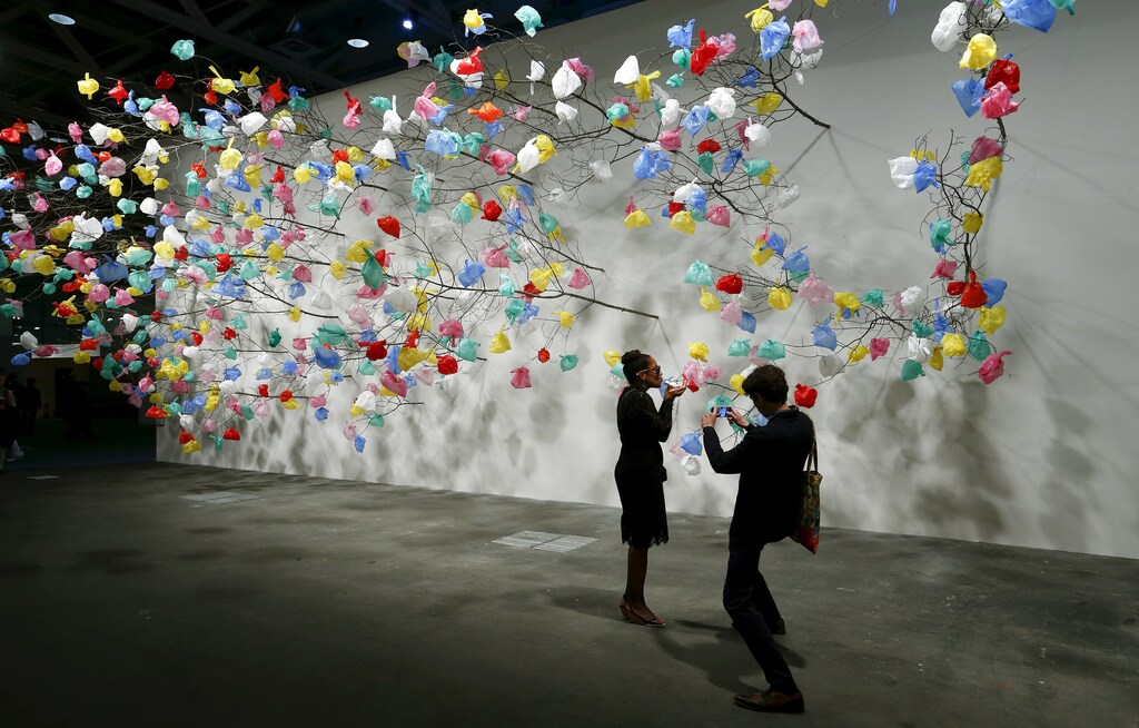 Visitors take a picture in front of the installation "Plastic Tree" by Cameroonian artist Pascale Marthine Tayou at the Art Unlimited exhibition at the Art Basel fair in Basel June 16, 2015. Founded by gallerists in 1970, the Art Basel is an international art show which is held annually in Basel, Hong Kong and Miami Beach. REUTERS/Arnd Wiegmann FOR EDITORIAL USE ONLY. NOT FOR SALE FOR MARKETING OR ADVERTISING CAMPAIGNS - GF10000129549