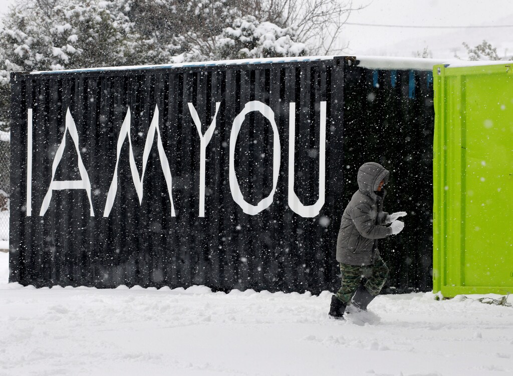 A stranded Syrian refugee boy walks through a snow storm at a refugee camp north of Athens, Greece January 10, 2017.REUTERS/Yannis Behrakis - RTX2YCJG