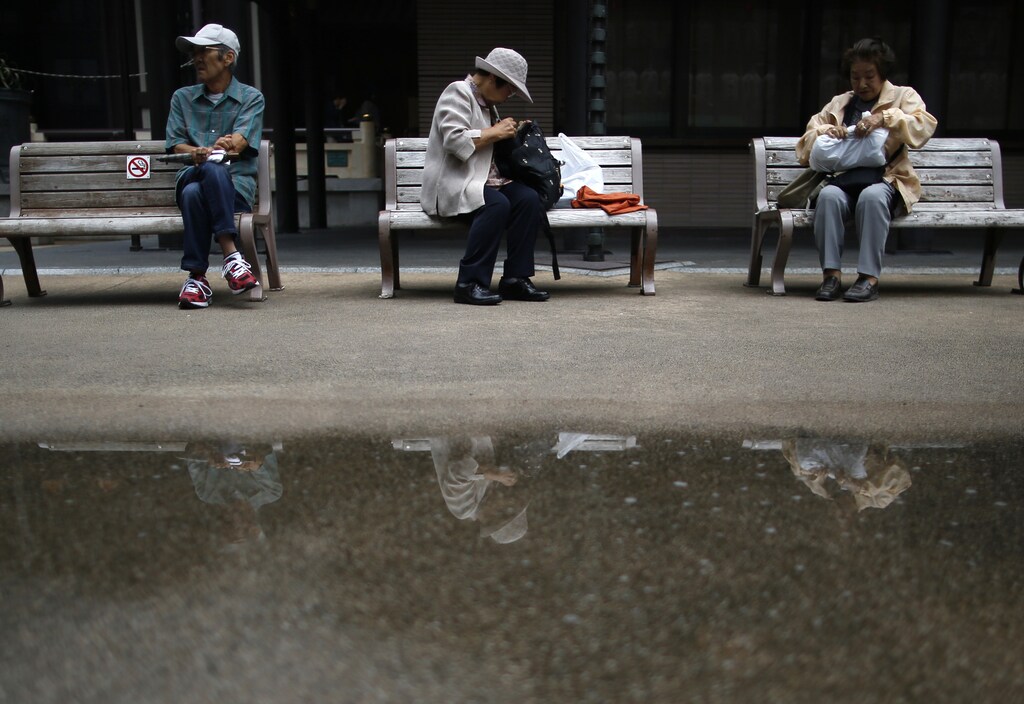 Elderly people take a break on bench seats at Tokyo's Sugamo district, an area popular among the Japanese elderly, in Tokyo August 29, 2014. REUTERS/Issei Kato