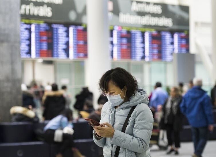 A woman wears a mask in the arrivals section of the international terminal at Toronto Pearson International Airport.