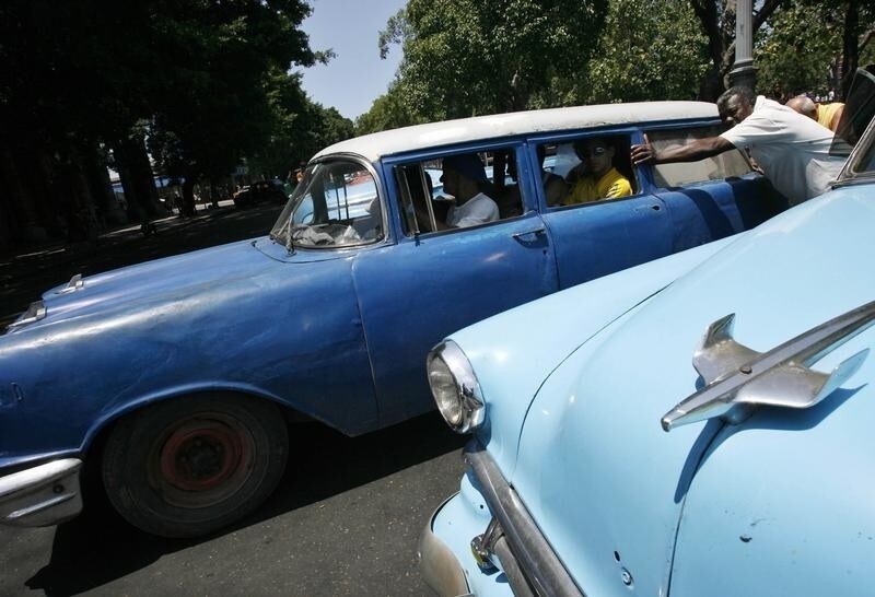 Men push a vintage car used as a taxi in Havana April 26, 2008. Cubans on both sides of the Florida Straits share a love for vintage American cars. In Miami, members of the Cuban community meet once a month to admire the old gas-guzzlers, while in the streets of Havana, 60,000 of those cars are a part of everyday city life