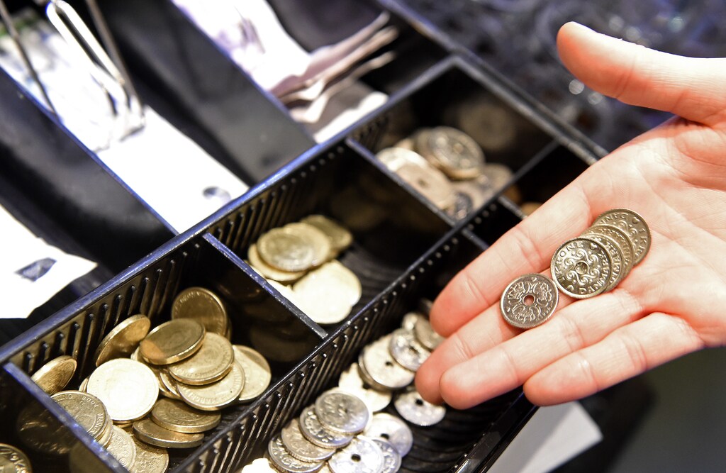 A waitress poses with some coins in front of a cash-box of Danish crowns in a pub in Copenhagen, January 22, 2015. The Danish central bank cut its key policy rate on Thursday for the second time this week to defend the crown's peg to the euro after the European Central Bank unveiled a stimulus package that weakened the single currency. REUTERS/Fabian Bimmer (DENMARK - Tags: BUSINESS) - GM1EB1N0K0J01