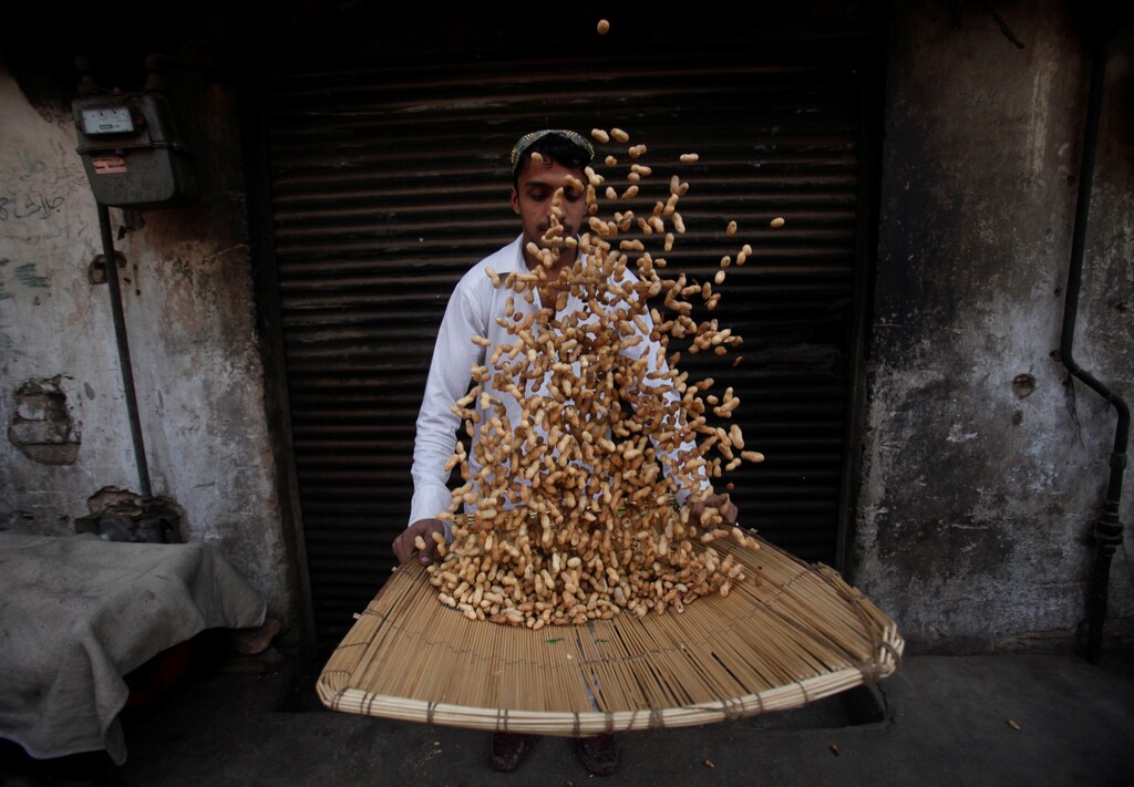 A man sorts through peanuts for sale at a shop in Peshawar, Pakistan January 5, 2017. REUTERS/Fayaz Aziz - RC1AD7B954E0