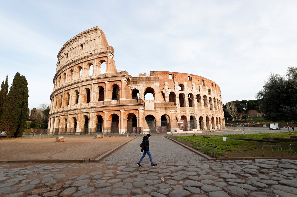 A person wearing a protective mask walks in front the Colliseum, the third day of an unprecedented lockdown across of all Italy imposed to slow the outbreak of coronavirus, in Rome, Italy, March 12, 2020. REUTERS/Guglielmo Mangiapane - RC2HIF9T7XQ8