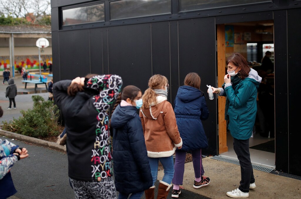 A teacher puts hydroalcoholic gel on the hands of schoolchildren as they enter in the classroom at a private school in Saint-Sebastien-sur-Loire near Nantes as France is seeing an increase in coronavirus disease (COVID-19) cases and hospitalisations, France, December 10, 2021. REUTERS/Stephane Mahe