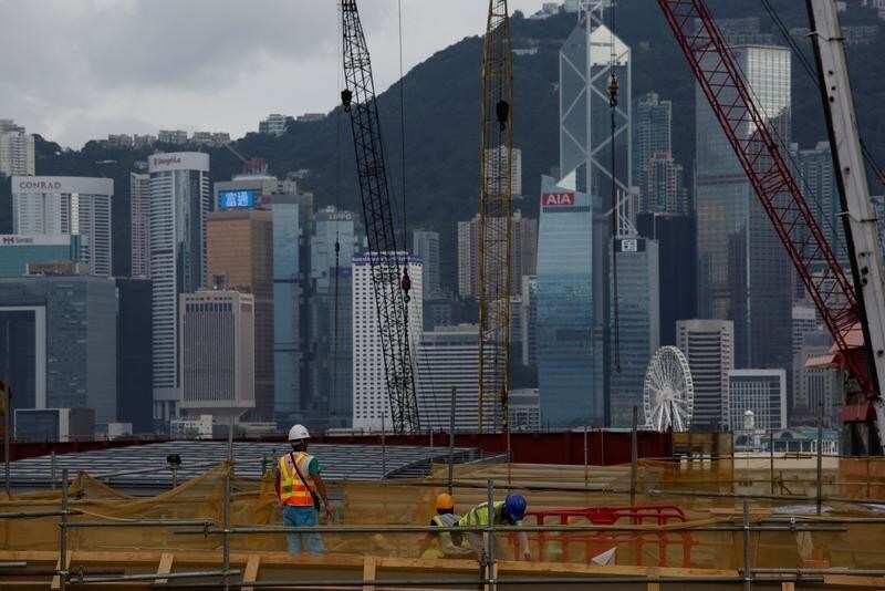 Workers at work at West Kowloon Terminus, under construction for the Guangzhou-Shenzhen-Hong Kong Express Rail Link, with a backdrop of the financial district in Hong Kong, China July 21, 2017. Picture taken July 21, 2017. REUTERS/Bobby Yip - RC19FC8DF3D0
