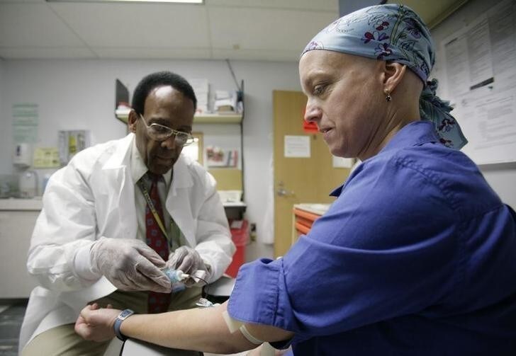 Phlebotomist Colliston Rose draws blood from cancer patient Deborah Charles during a weekly test to monitor blood counts at Georgetown University Hospital's Lombardi Cancer Center in Washington May 23, 2007. Since Charles, a journalist for Reuters, was diagnosed with breast cancer in November 2006, she has had to back away from actively covering the news and has had three operations, four rounds of chemotherapy and has been visiting the hospital at least once a week for appointments and treatment. Photo taken May 23, 2007. To match feature WITNESS-CANCER/DISCOVERY REUTERS/Jim Bourg (UNITED STATES)
