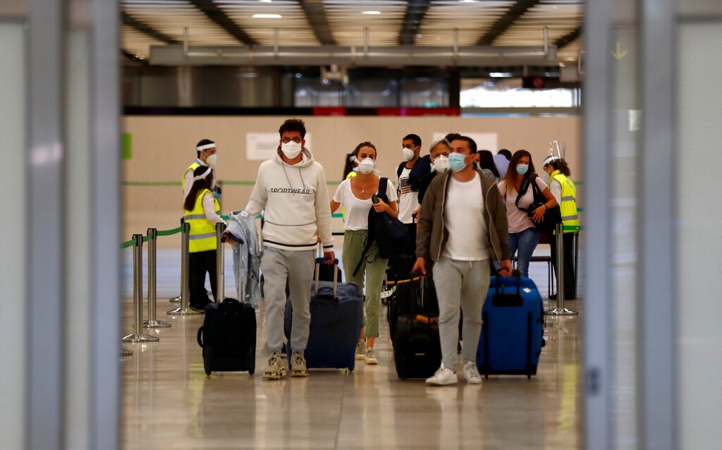 Pasajeros, con máscaras protectoras, caminan a su llegada desde París al aeropuerto Adolfo Suárez Barajas mientras España reabre sus fronteras a la mayoría de los visitantes europeos después del cierre del coronavirus, en Madrid, España, el 21 de junio de 2020.