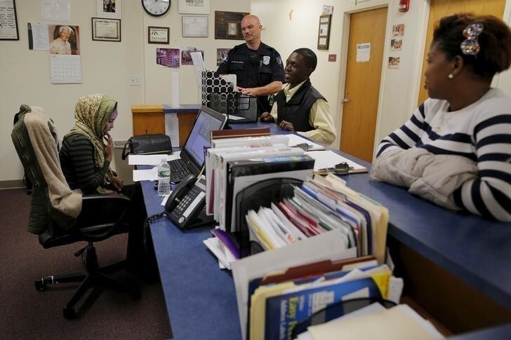 Lewiston Police Officer Patrick Griffin (top C), a community resource officer, talks to workers at the Maine Immigrant and Refugee Services facility in Lewiston, Maine June 1, 2015. One place in Lewiston where its growing diversity is not evident is the city's 82-member police force, but Chief Michael Bussiere aims to change that amid an intense national debate over race and policing. With about a quarter of his officers due to become eligible to retire in the next few years, Bussiere has begun reaching out to the region's 7,000-strong Somali population, including many who arrived in the United States as refugees from the East African country's long civil war. To match Feature MAINE-POLICE/REFUGEES Picture taken June 1, 2015. REUTERS/Brian Snyder