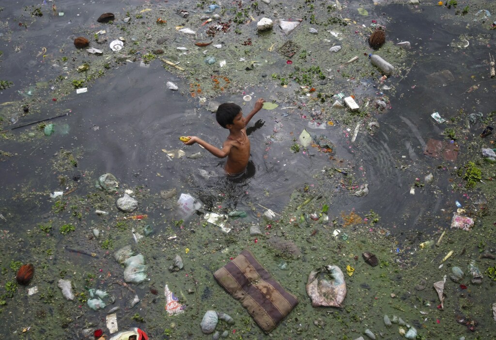 A boy throws a banana after collecting it from the polluted waters of river Sabarmati, in the western Indian city of Ahmedabad July 18, 2013.