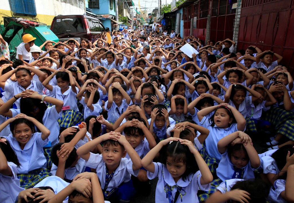 Students use their hands to cover their heads during an earthquake drill at the Baclaran Elementary School Unit-1 in Paranaque city, metro Manila, Philippines