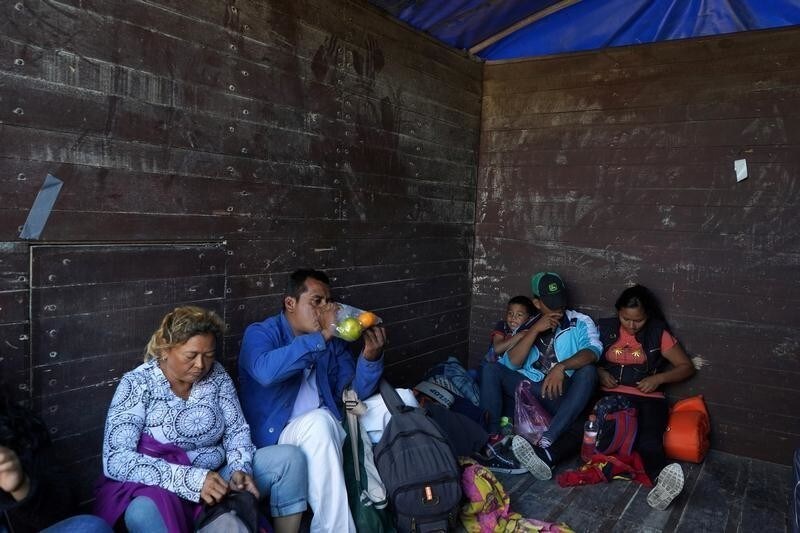 Migrants, part of a caravan of thousands traveling from Central America en route to the United States, sit in the back of a truck on the outskirts of Guadalajara, Mexico November 13, 2018.