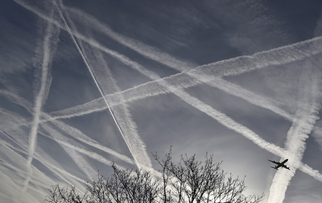 A passenger plane flies through aircraft contrails in the skies near Heathrow Airport in London, Britain, April 12, 2015. REUTERS/Toby Melville/File Photo - D1BEUDMTNTAB