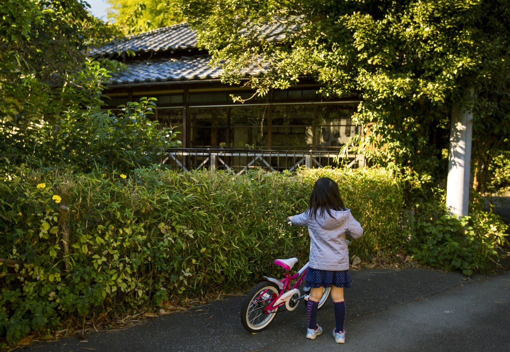 A girl looks at a vacant traditional Japanese wooden house in the town Kamakura outside Tokyo, November 15, 2014. Japan seems to have the right mix for developing a vibrant short-term home rental market: a rapidly growing tourism industry, a cheap currency and - unlike many countries - 8 million vacant homes. Picture taken November 15, 2014. REUTERS/Thomas Peter (JAPAN - Tags: BUSINESS REAL ESTATE) - GM1EACF0CPP01