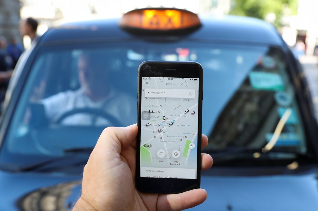 An Uber user in front of a black cab in London, June 2018.
