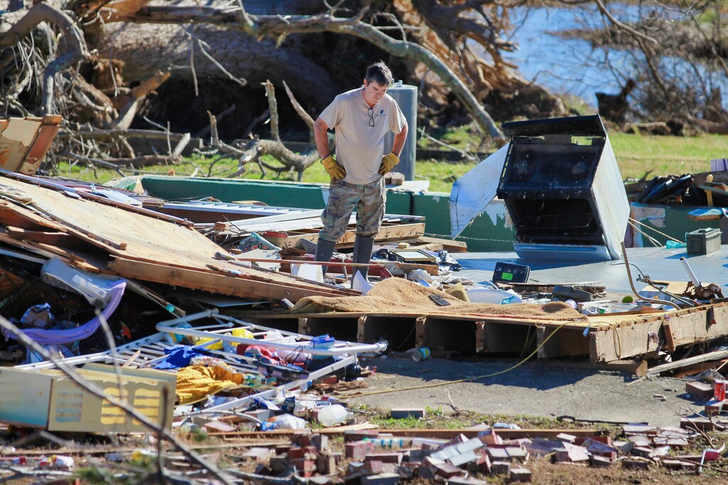 米国ケンタッキー州ケンブリッジショアーズで、竜巻被害を受けた家屋を見つめる男性。気候科学は、企業がレジリエンスの高い持続可能な経済システムを構築する上で重要な役割を果たします。