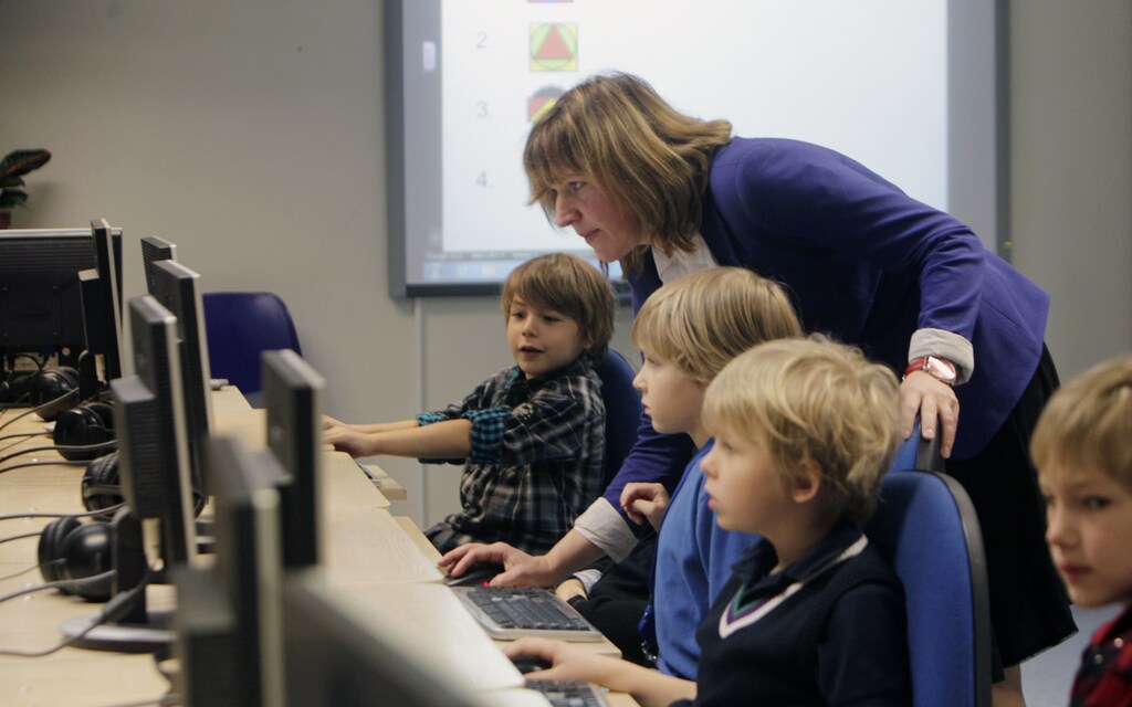 Teacher Kristi Rahn (C) helps to first grade students during a computer lesson in school in Tallinn September 25, 2012. Estonian Tiger Leap Foundation has launched a program called "ProgeTiiger" where Estonian students will be introduced to computer programming and creating web and mobile applications. According to representatives from the foundation, the program will start with students in the first grade, which starts around the age of 7, and will continue through a student's final years of public school, around age 15. REUTERS/Ints Kalnins (ESTONIA - Tags: EDUCATION SCIENCE TECHNOLOGY) - GM1E89P1PG901
