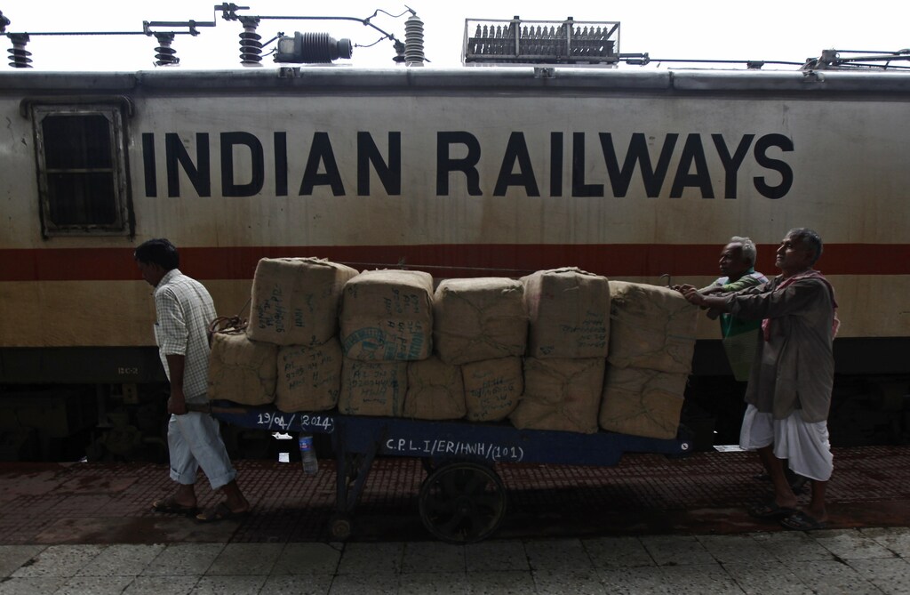 Porters transport goods on a hand-pulled trolley to load onto a train at a railway station in Kolkata July 8, 2014. Indian Prime Minister Narendra Modi's government disappointed markets with its first major economic policy statement on Tuesday, promising to seek foreign and private funding for the railways but giving no details of how it would lure investors. India's state-owned railways are the fourth-largest in the world. They have suffered from years of low investment and populist policies that have kept fares low. REUTERS/Rupak De Chowdhuri (INDIA - Tags: TRANSPORT BUSINESS POLITICS) - RTR3XN4H