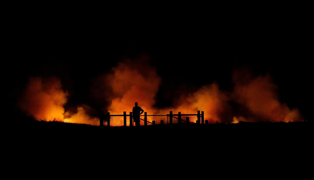 A man watches a bushfire burning on the Kurnell Peninsula, during an unseasonably warm start to Spring, on Sydney's southern coast, Australia September 3, 2017. REUTERS/Jason Reed TPX IMAGES OF THE DAY - RC18DF465EB0