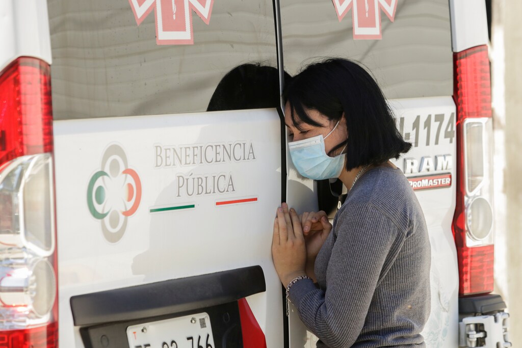 Una mujer se inclina en la puerta de una ambulancia que transporta el cuerpo de un hombre que murió de la enfermedad coronavirus (COVID-19) antes de ser trasladado a un hospital, en Ciudad Juárez, México, el 26 de mayo de 2020.