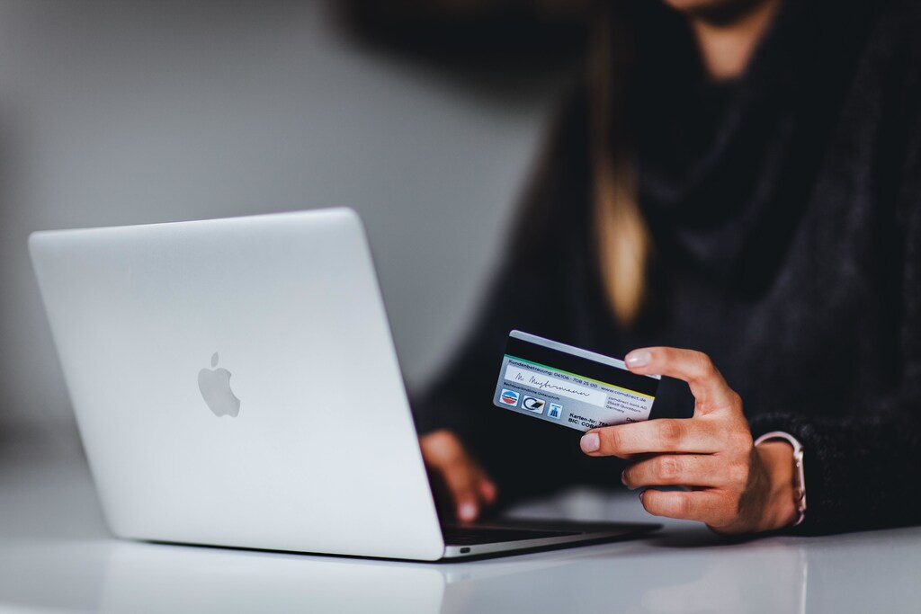 a picture of a woman using her credit card to buy something online