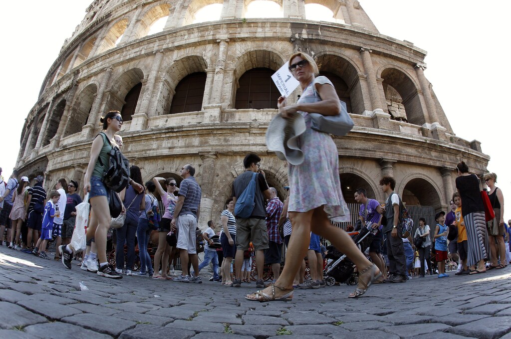 Tourists walk in front of Rome's ancient Colosseum, July 30, 2012. The ancient Colosseum of Rome, where gladiators fought for their lives, is slanting about 40 cm (16 inches) lower on the south side than on the north, and authorities are investigating whether it needs urgent repairs. REUTERS/Alessandro Bianchi (ITALY - Tags: CITYSPACE SOCIETY TRAVEL) - RTR35MVF