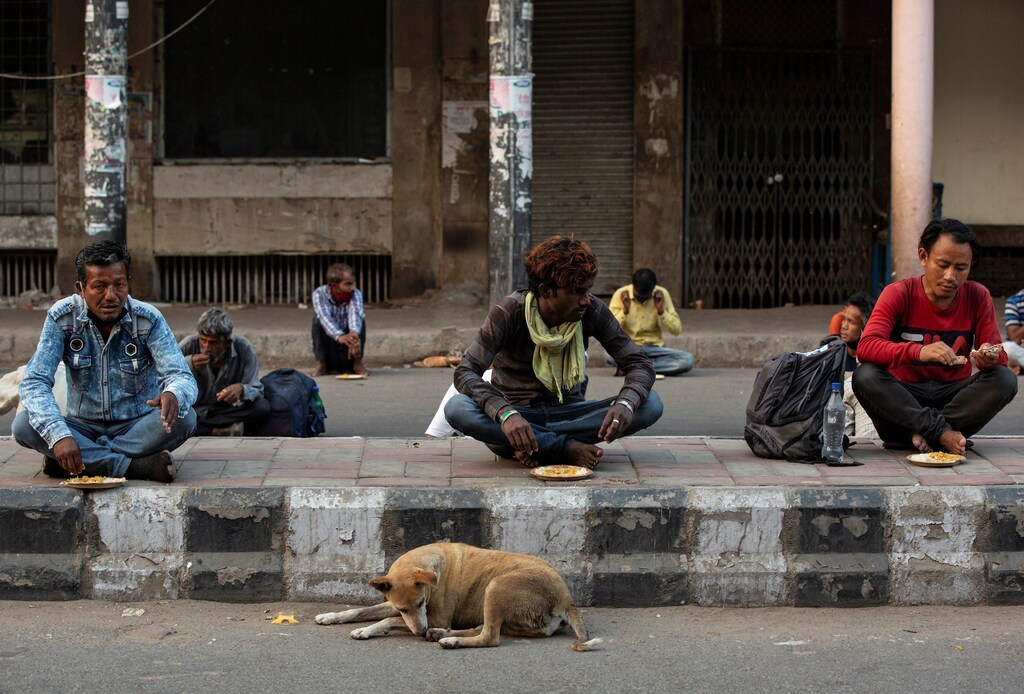 Daily wage labourers and homeless people eat food distibuted by a non-governmental organisation during an extended nationwide lockdown to slow the spread of the coronavirus disease (COVID-19) in New Delhi, India, April 28, 2020. REUTERS/Danish Siddiqui - RC2QDG90ZBUV