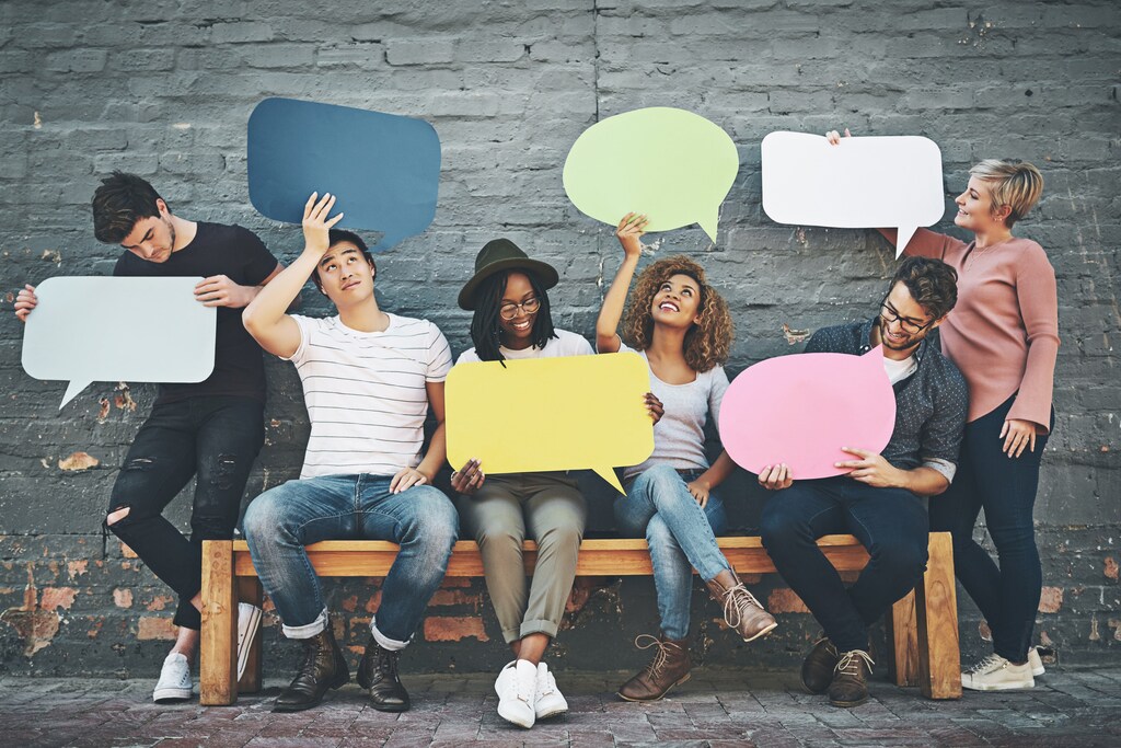 Shot of a diverse group of people holding up speech bubbles outside - inclusive systems, gender equality