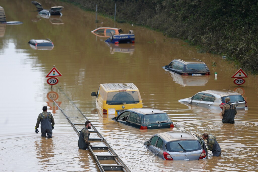 Members of the Bundeswehr forces, surrounded by partially submerged cars, wade through the flood water following heavy rainfalls in Erftstadt-Blessem, Germany